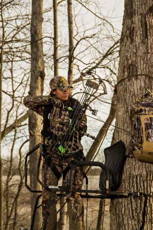 woman bowhunting in a tree stand
