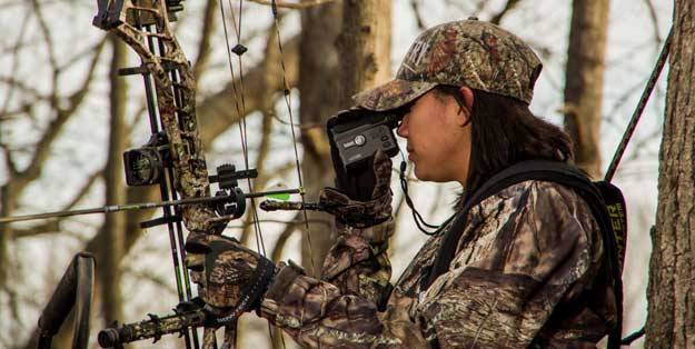 female hunter in tree stand with bow