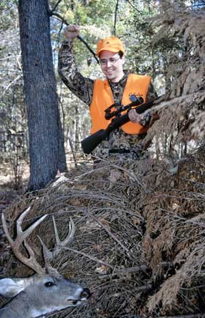 hunter with buck in fallen tree