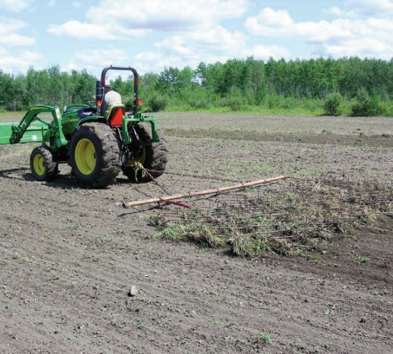 Gamekeeper using a harrow to pull up weeds and grasses