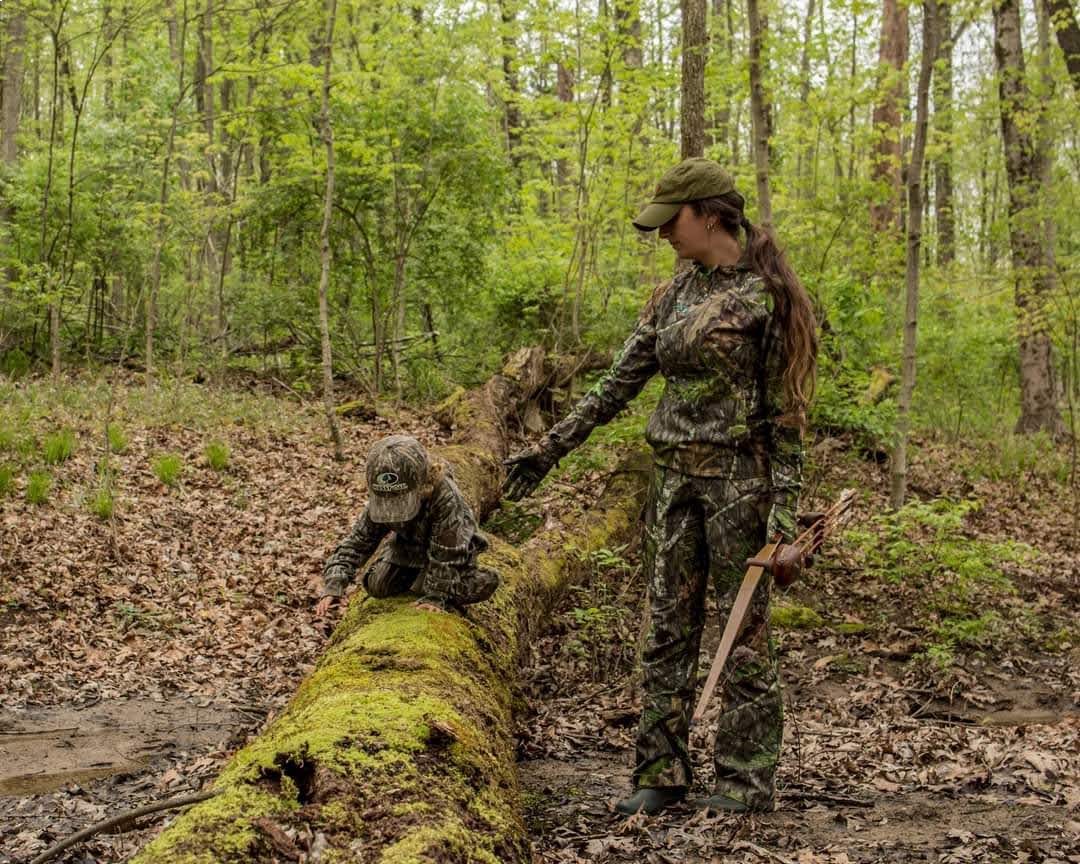 beka garris helps her daughter over a log