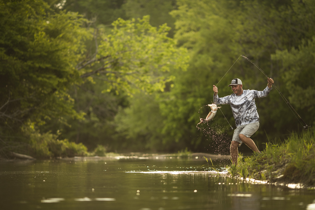 man catching a catfish on the bank