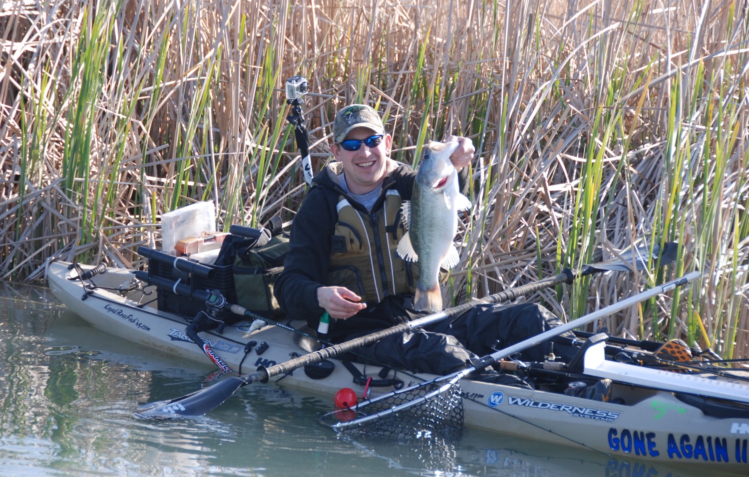 man holding up fish in a kayak