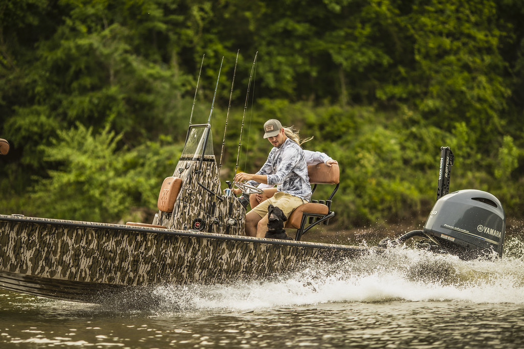 men drive a camo boat on the river