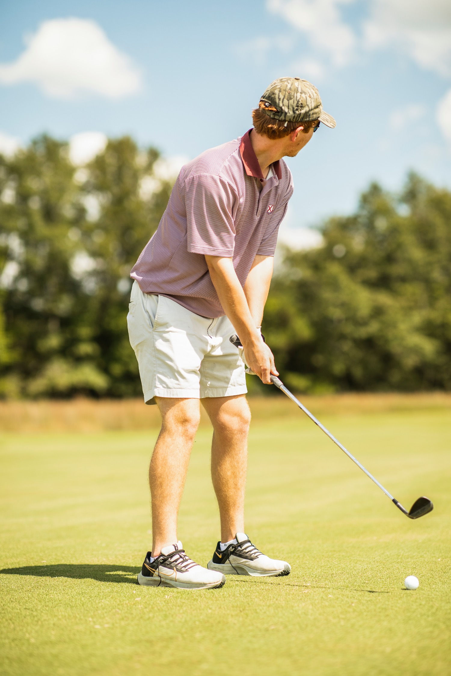 golfer waits to swing with a bottomland hat on