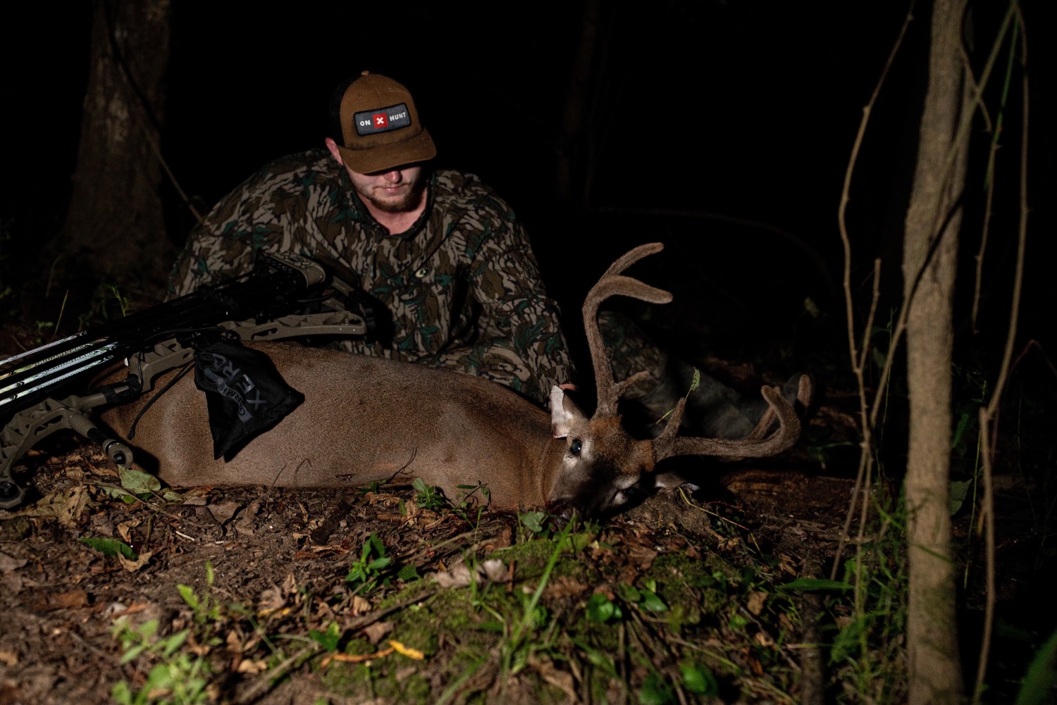 man in mossy oak camo holds velvet buck